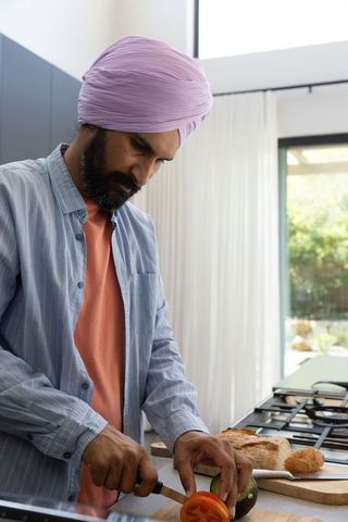 Mid adult indian man cooking in modern home kitchen