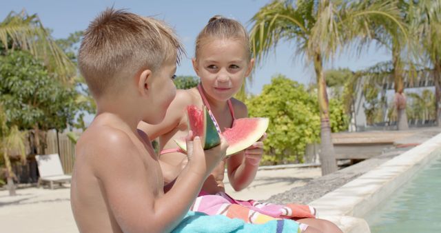Happy caucasian siblings eating watermelon at swimming pool at beach house. Vacation, free time, summer and childhood.