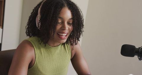 African American woman hosting podcast wearing headphones at microphone in home studio