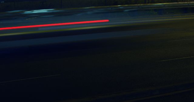 Blurred light trails from vehicles captured at night on a city highway create an abstract and dynamic scene. Ideal for use in projects related to technology, urban life, transportation, speed, and motion. Perfect for backgrounds, presentations, websites, and promotional materials.