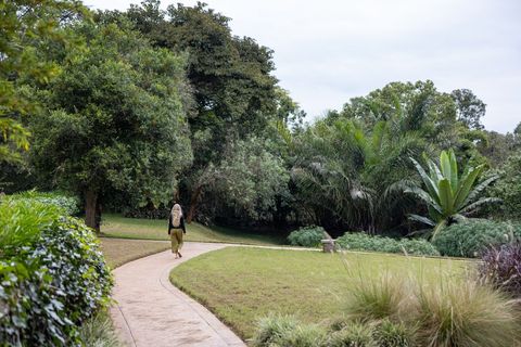 Woman Walking Along Path in Lush Green Park
