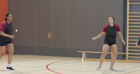 Diverse female teammates warming up on indoor court wearing matching training uniforms