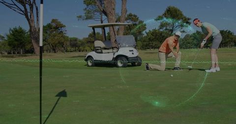 Golf partners align ball on sunlit course next to cart