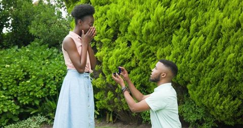 Man Proposing to Surprised Woman in Lush Green Garden