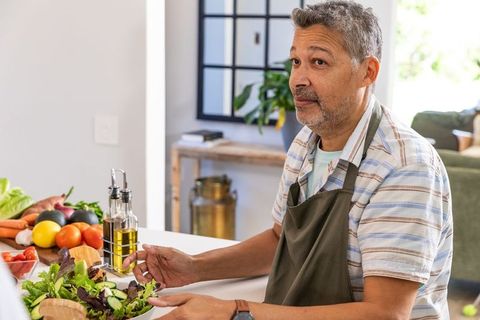 Middle-Aged Man Tossing Salad at Home Kitchen Counter