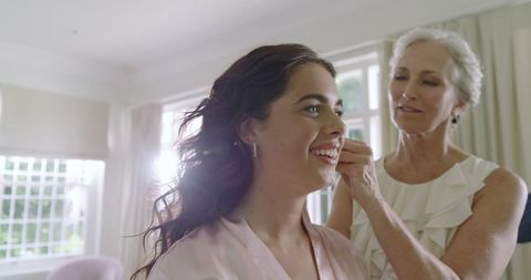Mother Helping Bride Get Ready for Wedding Day in Sunny Room