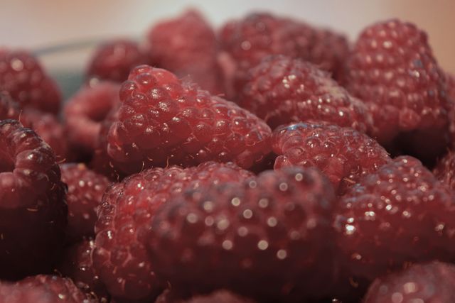 Fresh ripe raspberries piled together. Perfect for use in food blogs, recipe websites, health and wellness articles, or as a background image related to gardening and organic produce.