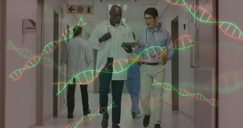 Physicians walking and reviewing genomic data on tablet in hospital corridor for genomics care