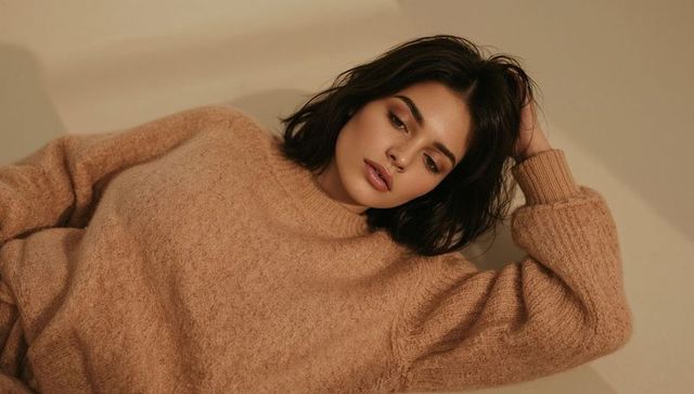 Serene woman reclining in camel fuzzy sweater conveying cozy autumn fashion, beauty, warmth