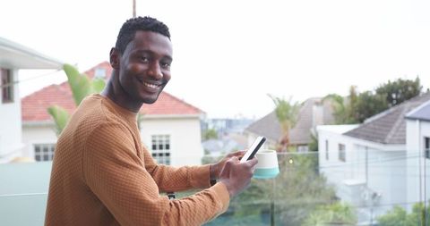 Mid-adult man enjoying leisure on residential balcony with coffee