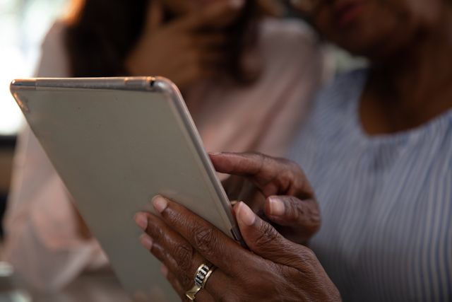 African American mother and adult daughter using a digital tablet. Domestic life and senior people using technology. 