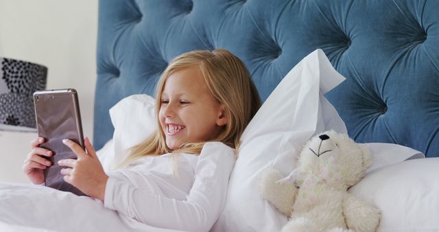 Happy Little Girl Relaxing in Bed and Playing with Tablet - Download Free Stock Images Pikwizard.com