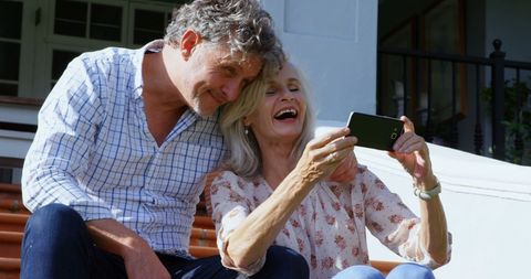 Senior Couple Laughing While Taking Selfie on Porch