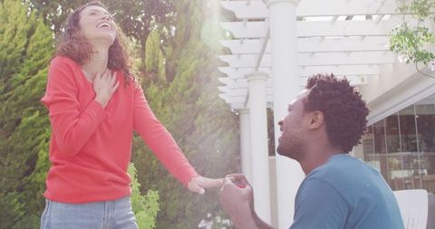 Man proposing with engagement ring bringing joyful surprise to partner