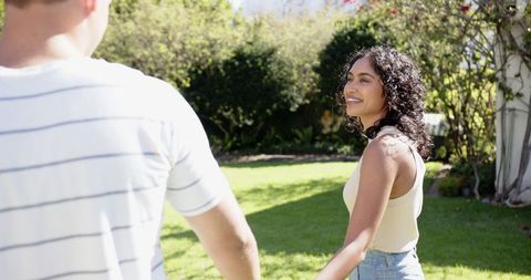 Couple walking hand in hand in sunlit garden outdoors