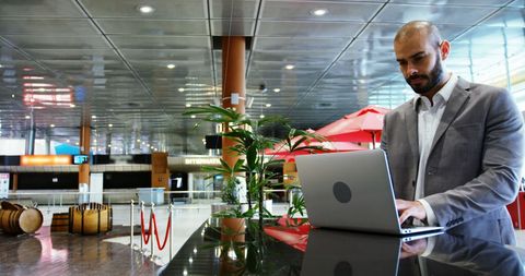 Businessman in Airport Terminal Working on Laptop