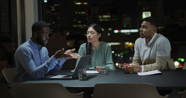 Image of african american businessman talking to two diverse colleagues at night in office meeting. Business, communication, inclusivity and flexible working concept digitally generated image.