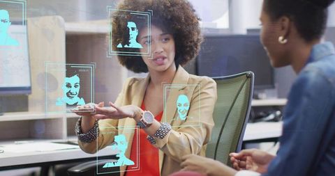 Businesswomen presenting biometric facial recognition interface collaborating in office