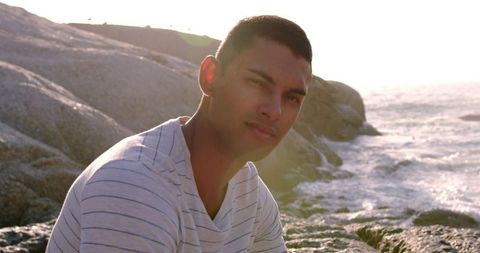Confident Young Man Relaxing on Beach Rocks in Sunshine - Download Free Stock Images Pikwizard.com