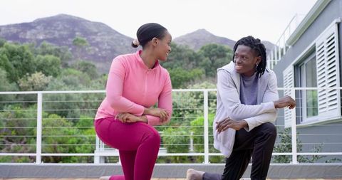 African American friends stretching on deck overlooking hills during outdoor fitness session