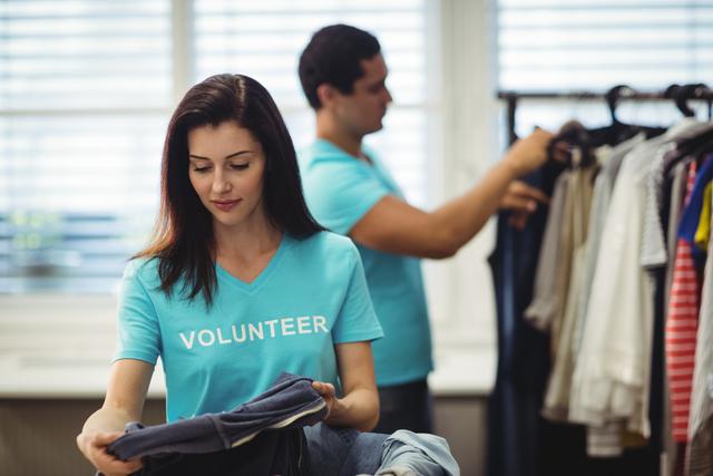 Beautiful female volunteer checking clothes in workshop