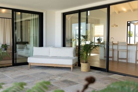 Minimalist patio with white cushioned bench, sliding glass doors and sunlit kitchen view