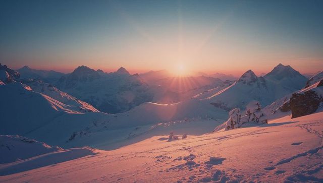 Sunrise over snowy alpine landscape with rocky outcrop