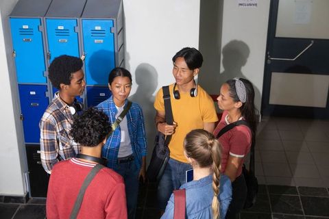 Diverse Teenagers Chatting in Hallway Next to Blue Lockers