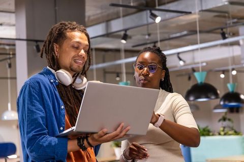 African american coworkers collaborating over laptop in modern office workspace