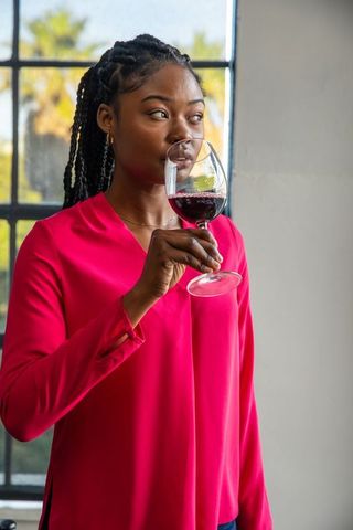 African American Woman Enjoying Red Wine by Sunlit Window
