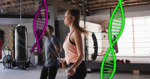Young woman and man skipping rope in boxing gym with colorful dna helix overlay