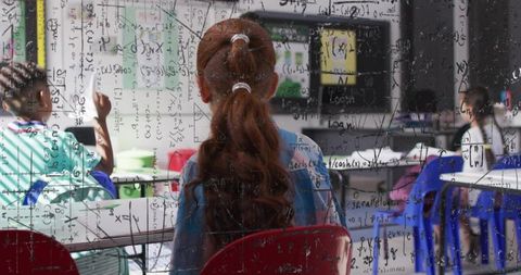 Red-haired student concentrating in modern classroom with digital math equations overlay