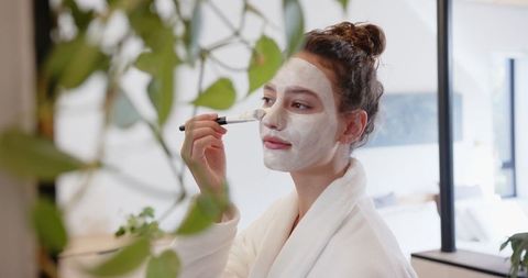 Woman Applying Facial Mask in Cozy Bathroom