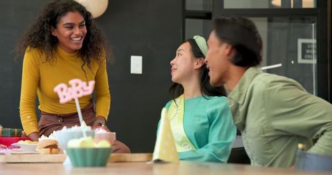 Cheerful multiracial colleagues hosting office baby shower celebration