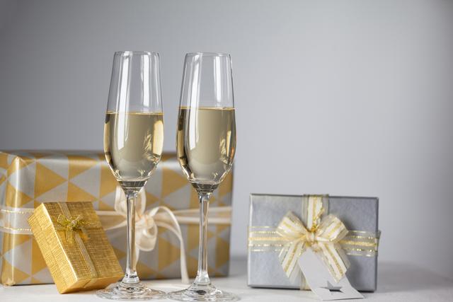 Two champagne flutes and Christmas gifts against white background