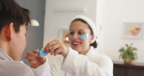 Couple sharing at-home spa routine with blue under-eye patches in white robes