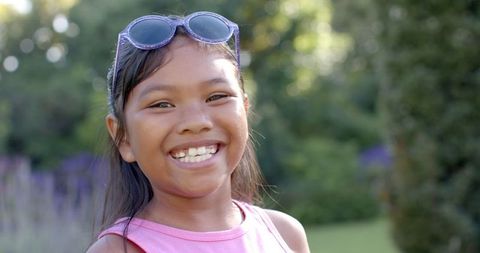 Joyful Girl with Sunglasses Enjoying Sunny Outdoor Garden