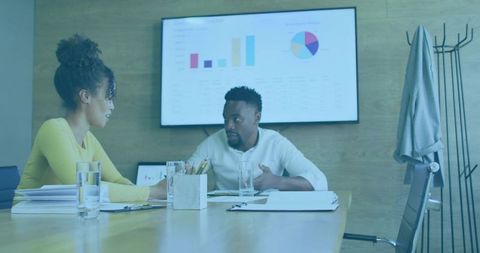 Colleagues discussing charts and documents during collaborative boardroom meeting