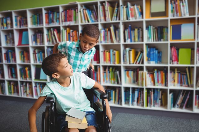 Two boys in a library, one sitting in a wheelchair holding books while the other stands beside him. This image can be used to promote inclusive education, diversity, and the importance of reading and learning among children. Ideal for educational materials, library promotions, and awareness campaigns about accessibility and inclusion.