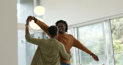 African American Couple Dancing in Bright Modern Living Room with Floor-to-Ceiling Windows