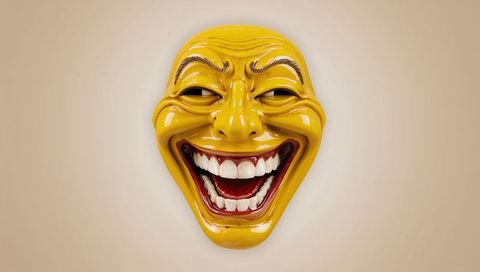 Glossy yellow laughing mask sculpture with wide white teeth and expressive brows