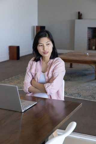 Asian woman working at home on laptop in modern minimalist setting