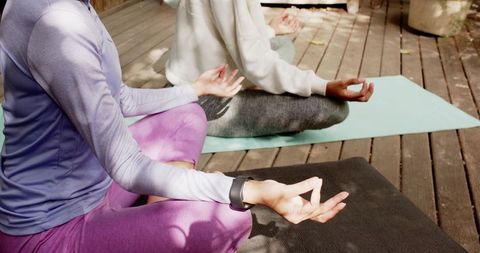 Friends Meditating Outdoors on Wooden Deck with Yoga Mats