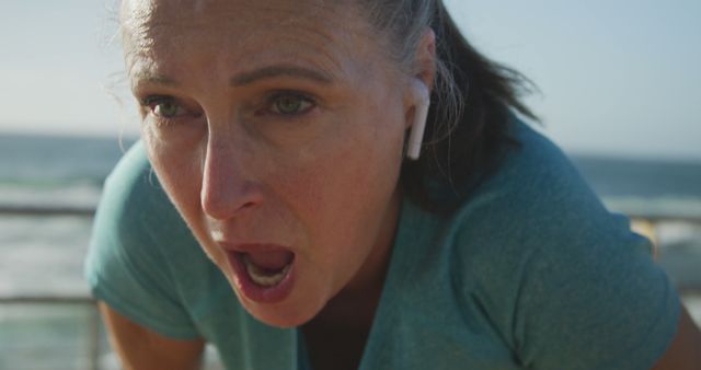 Mature Woman Exercising with Earbuds by Ocean - Download Free Stock Images Pikwizard.com