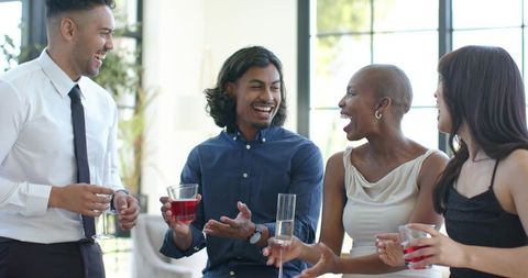 Diverse professionals chatting and laughing at networking reception in modern lounge
