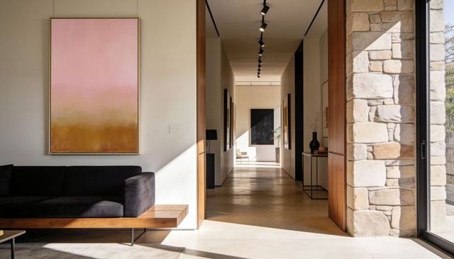 Minimalist modern hallway guiding eye with pink gold abstract, black sofa and stone wall