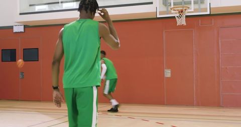Diverse male teammates practicing basketball passing and fake shot drill in indoor gym