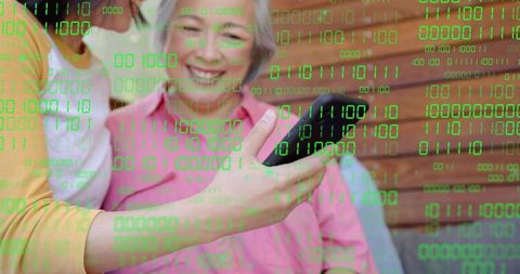 Smiling Asian Senior Using Smartphone with Green Binary Code Overlay for Digital Technology