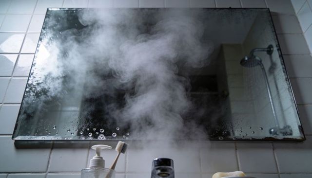 Fogged bathroom mirror with steam, toothbrush and soap at sink