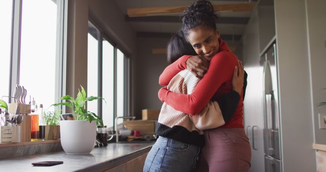 Image of happy biracial female friends embracing. Friendship, having fun and spending quality time together at home.